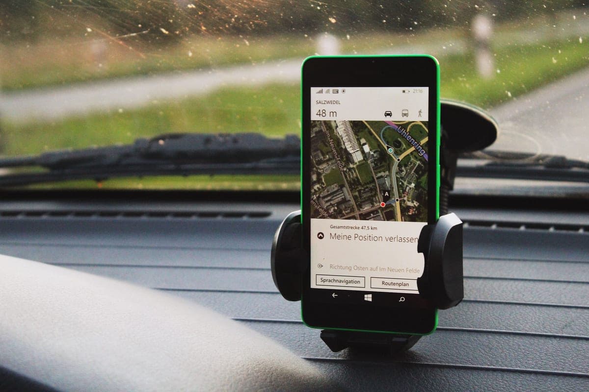 A smartphone mounted on a car dashboard showing navigation
